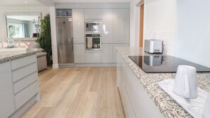 A modern kitchen with a stainless steel refrigerator, built-in oven, and microwave. - Little Roskrow (Penryn)