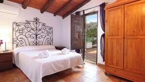 A bedroom with a bed, wooden wardrobe, and a balcony with a view of the mountains. - Villa Martorellet, Villa near Cala Sant Vicenç and its beaches (Cala Sant Vicenç)