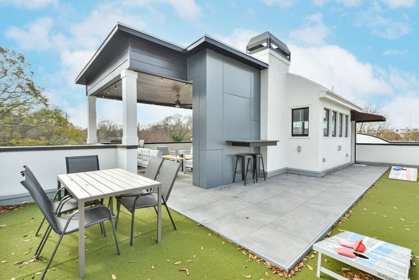 A modern rooftop patio with a dining table, chairs, and a bar area.