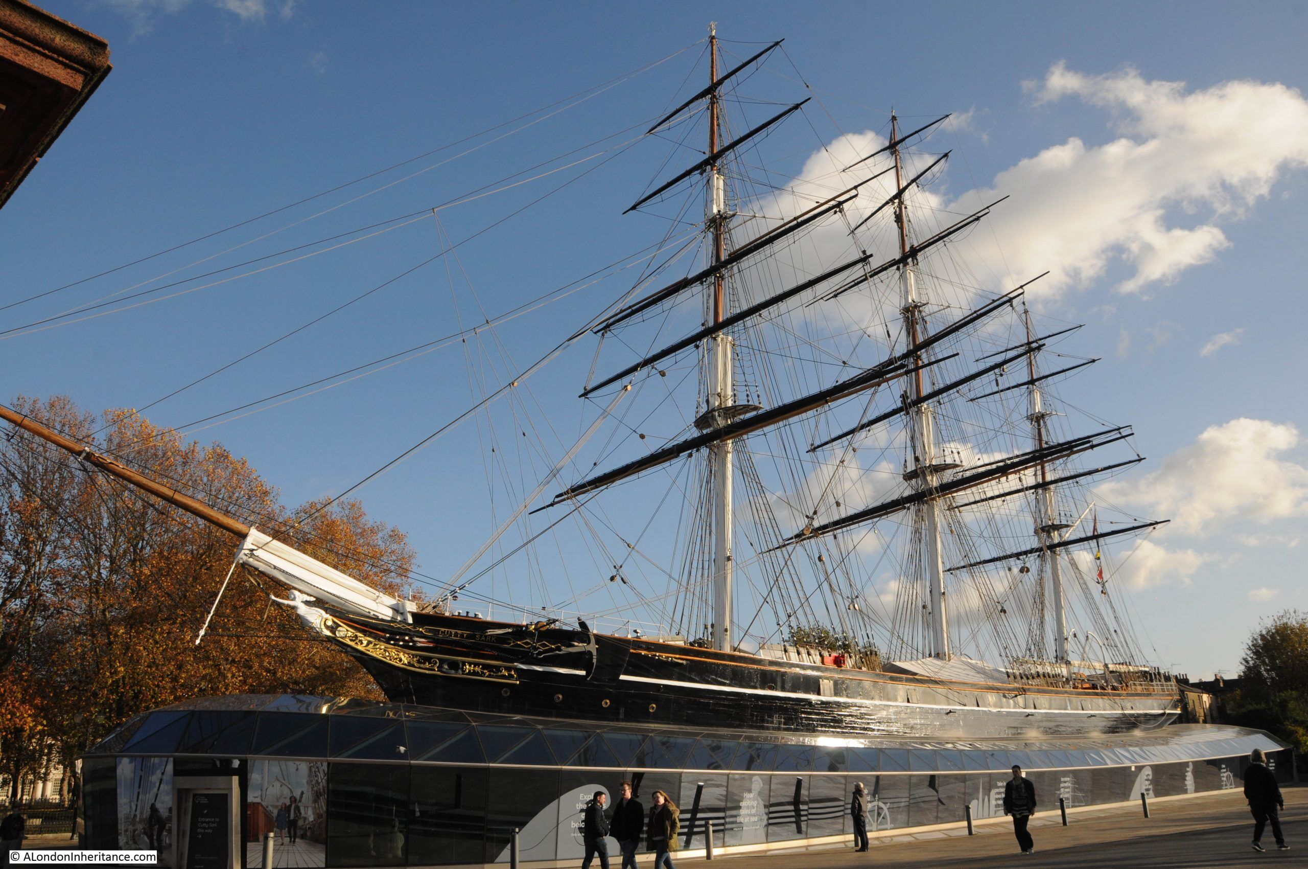 A tall ship docked at a port with a glass barrier in front.