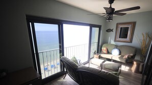 Un balcon avec vue sur l’océan, un canapé, un fauteuil et un ventilateur de plafond.