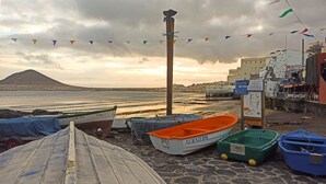A beach with boats, a mountain, and buildings in the background. - Daydream El Medano Coliving (Granadilla de Abona)