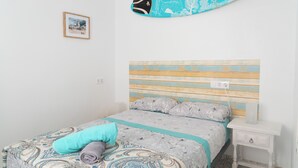 A bedroom with a bed, a nightstand, a surfboard, and a framed picture on the wall. - Daydream El Medano Coliving (Granadilla de Abona)