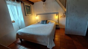 Un dormitorio con una cama, dos lámparas de noche, un cuadro en la pared y una ventana con cortinas.