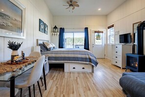 Un dormitorio con cama, televisor, chimenea y balcón con cortinas.