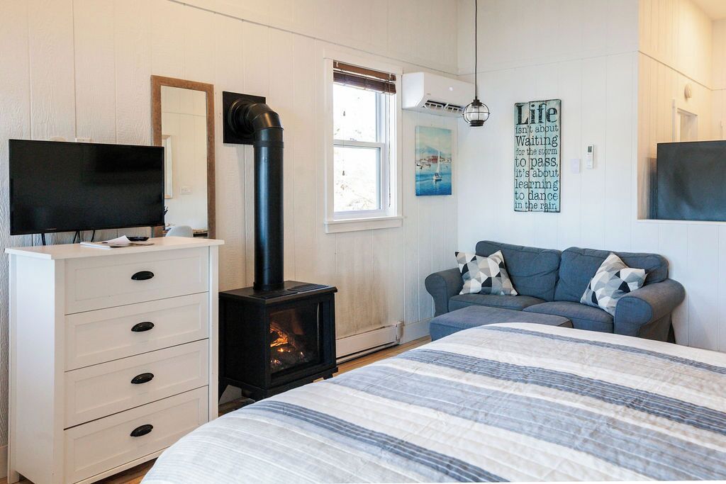 Une chambre à coucher comprenant un lit, une commode, un téléviseur, une cheminée, un canapé et une fenêtre.