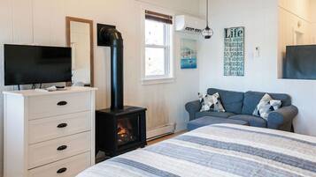 Une chambre à coucher comprenant un lit, une commode, un téléviseur, une cheminée, un canapé et une fenêtre.