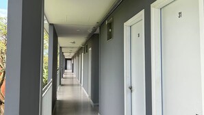 A long, narrow corridor with doors on one side and a balcony on the other. - Hotel Penedo Inn (Itatiaia)