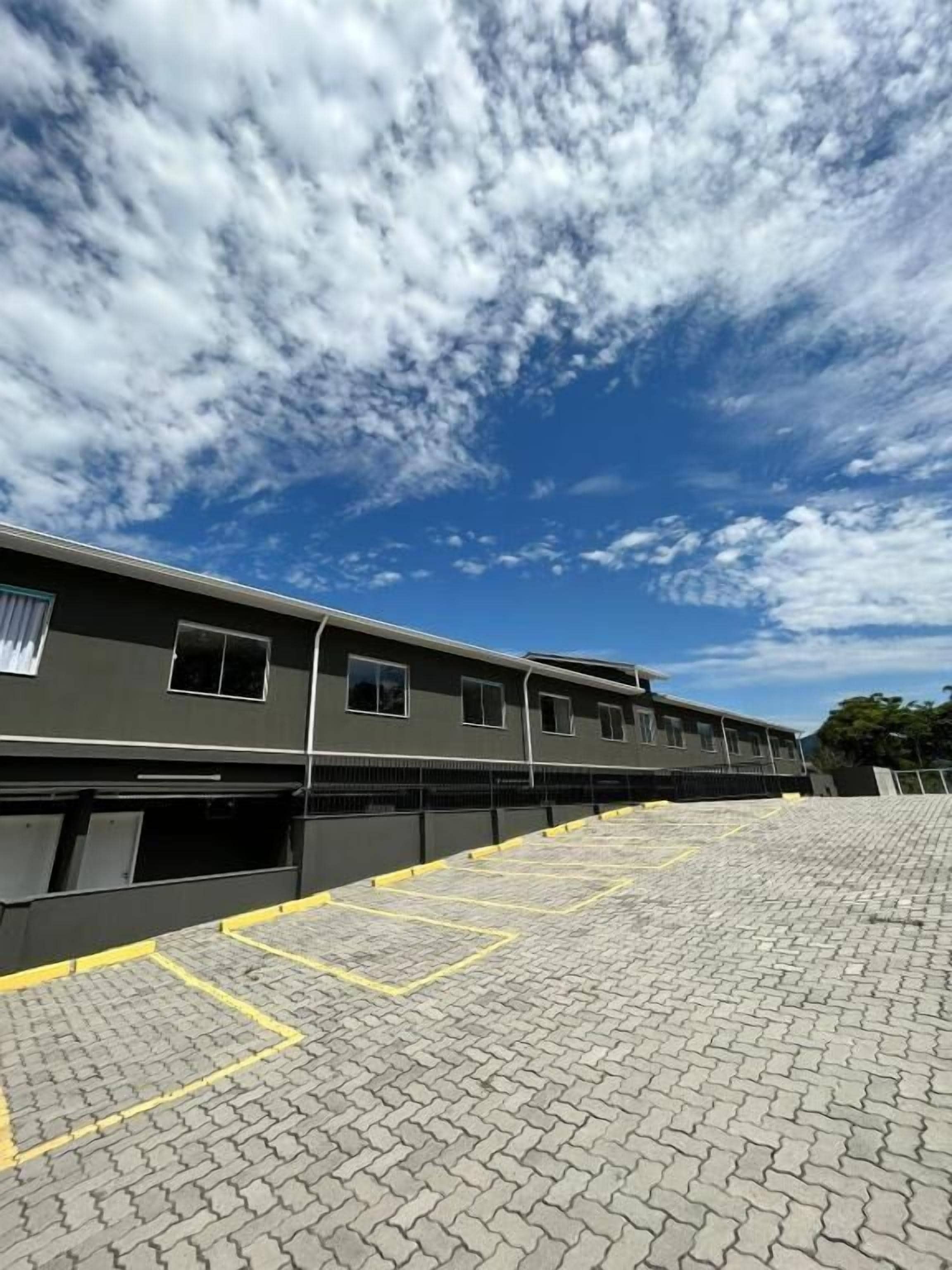 A building with a flat roof and a paved parking area with yellow lines.