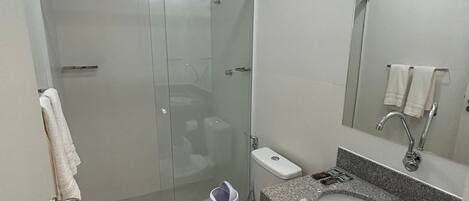 A modern bathroom with a glass-enclosed shower, a white toilet, a granite sink, and a mirror above the sink.