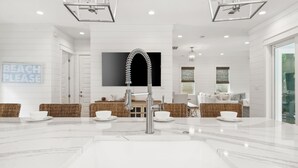 Una cocina moderna con una isla central, muebles blancos y un lavamanos grande.