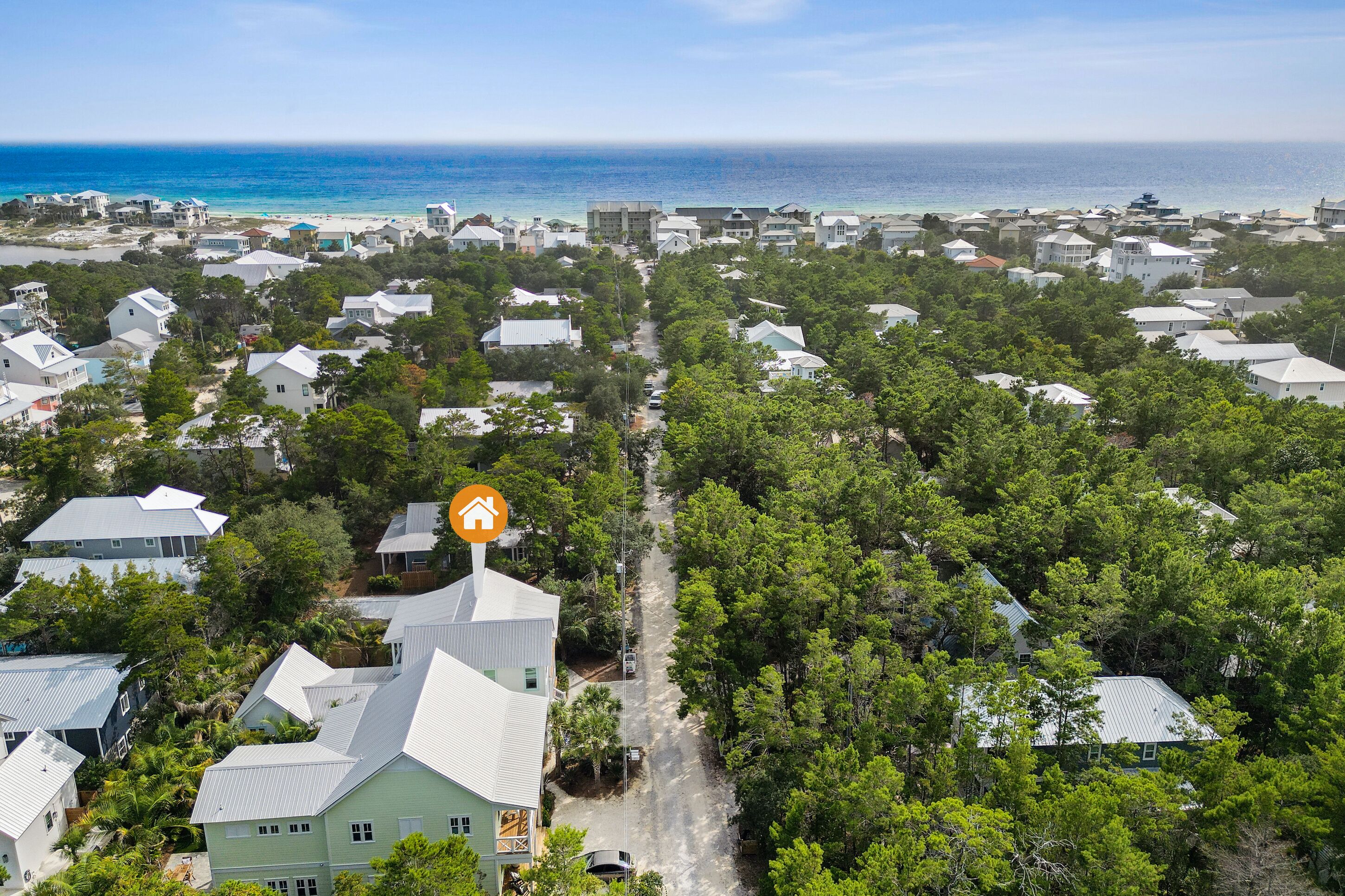 A coastal residential area with houses, a clear view of the ocean, and a central road.
