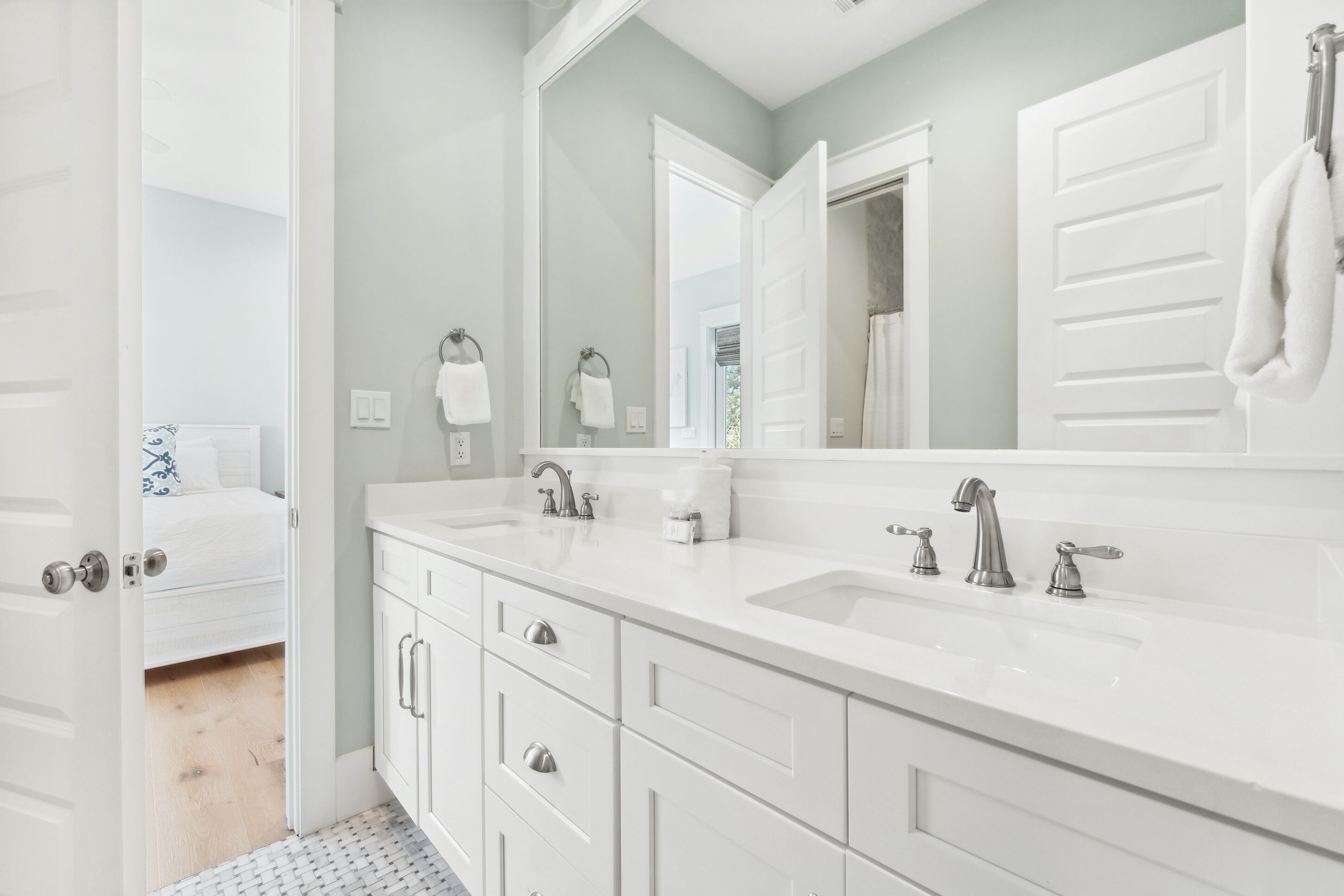 A modern bathroom with a white vanity, two sinks, and a large mirror.