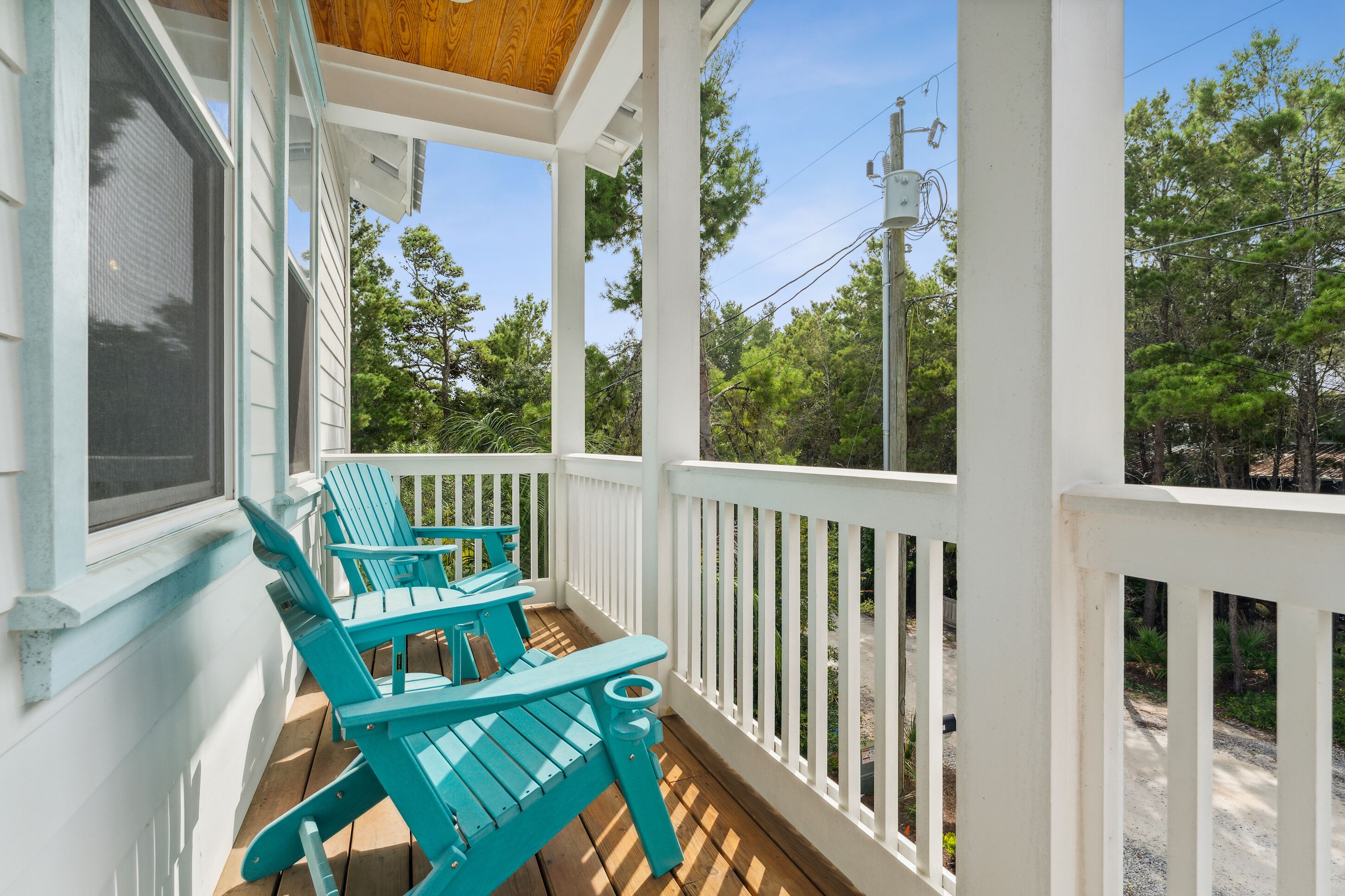 A covered porch with white railings and a wooden ceiling.