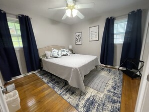 A bedroom with a bed, a ceiling fan, a window with curtains, and a rug. - Charming Ranch near Hartsfield!
(College Park)
