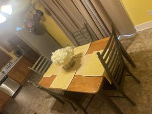 A dining table with a vase of flowers, yellow placemats, and wooden chairs. - Charming Ranch near Hartsfield!
(College Park)