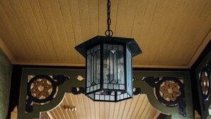 A corridor with a hanging lantern, brick walls, and decorative wooden panels.