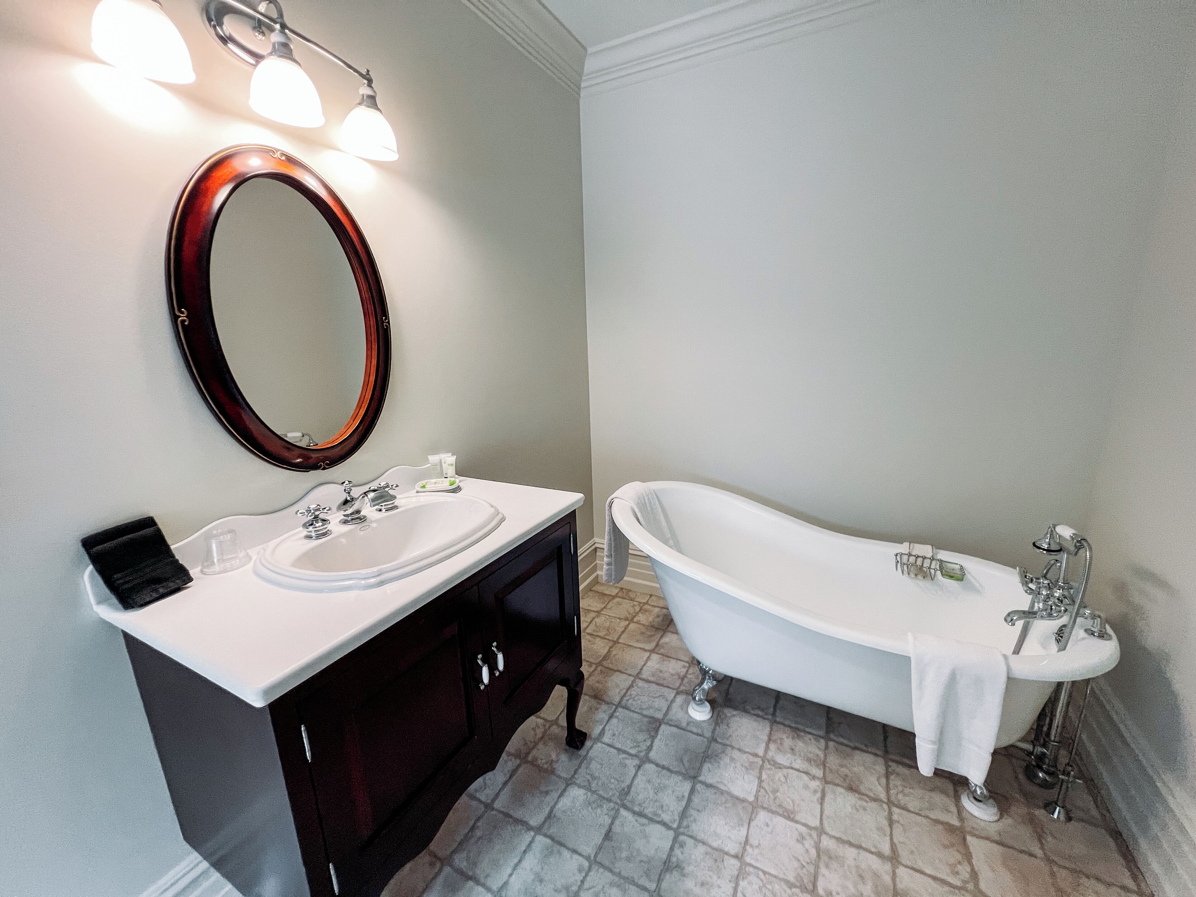 A bathroom with a freestanding bathtub, a vanity with a mirror, and a sink.