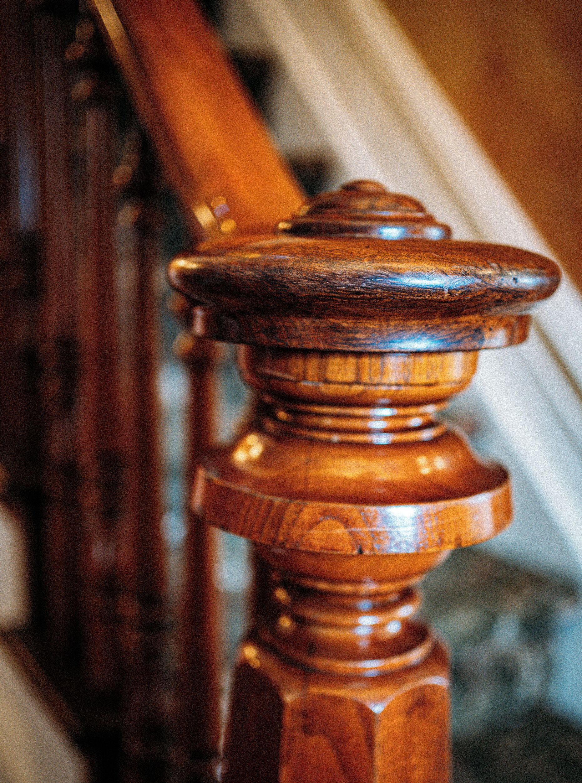 Een houten balustrade met gedetailleerde houtsnijwerken en een afgeronde knop.