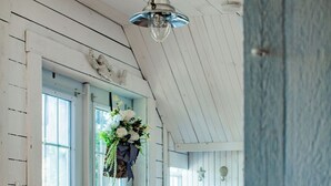 A room with wooden walls, a hanging flower arrangement, a ceiling light, and a door with glass panels.