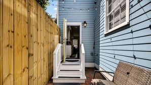 Une clôture en bois, un escalier blanc et une chaise en osier dans un jardin.