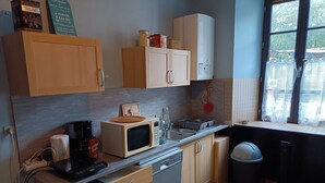 A compact kitchen with wooden cabinets, a microwave, a coffee maker, and a sink. - Maison Éclusière Napoléonienne, Havre de Paix au Bord du Canal D'ille et Rance (Hédé-Bazouges, Hédé)