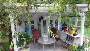 A covered patio with a table and chairs, surrounded by potted plants and a birdcage. - Maison Éclusière Napoléonienne, Havre de Paix au Bord du Canal D'ille et Rance (Hédé-Bazouges, Hédé)