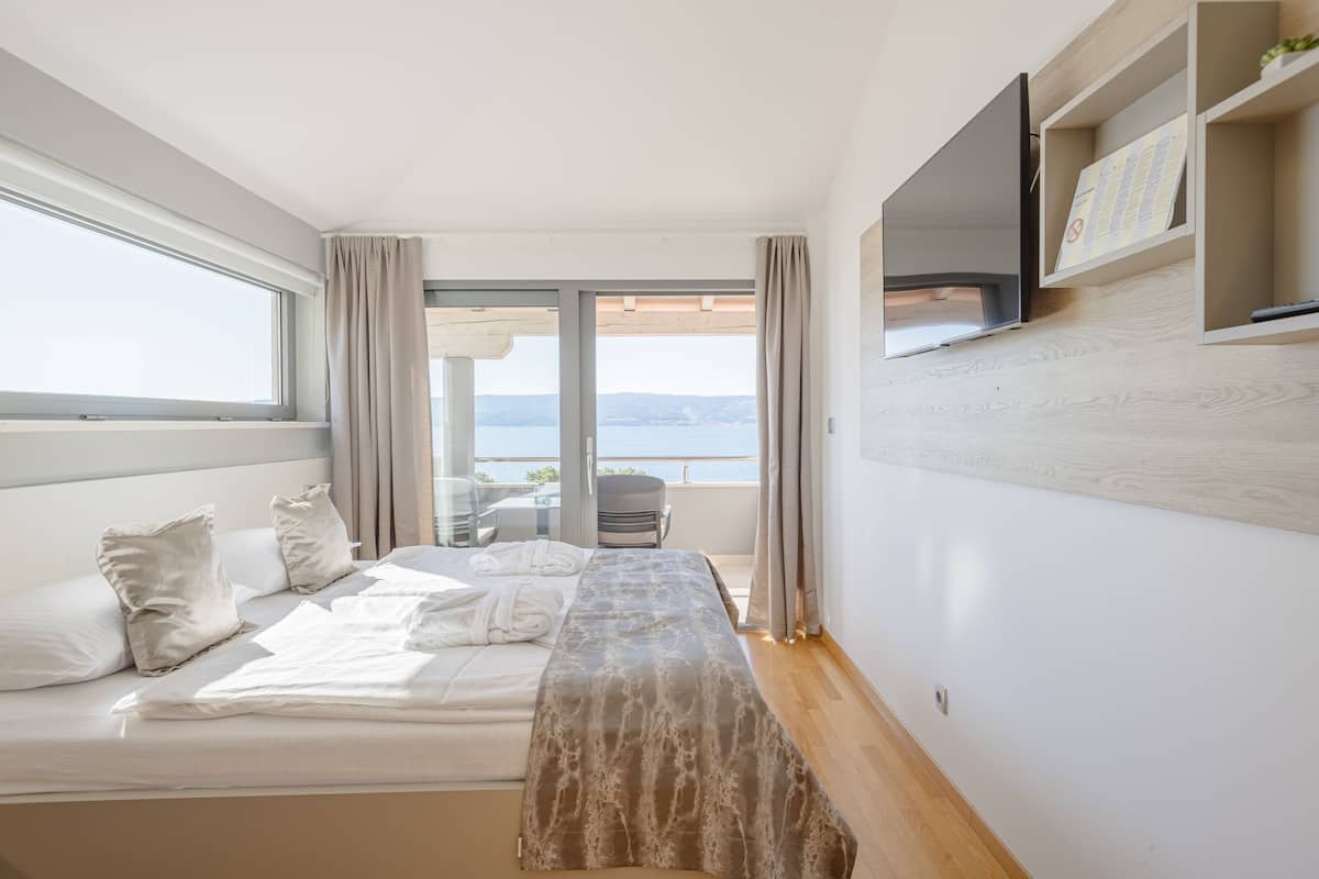 Quarto de hotel moderno com uma cama, uma escrivaninha e vista para o mar.