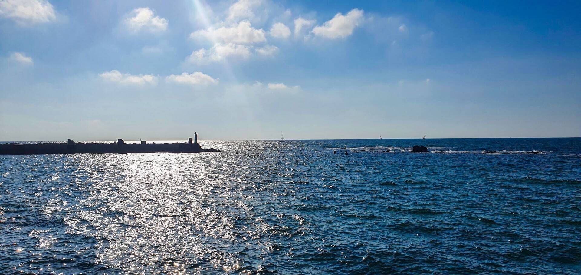 Une vue sur la côte, avec un phare et une jetée qui s’avance dans la mer.