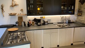 Eine moderne Küche mit dunklen Schränken, einem Gasherd und einem eingebauten Backofen.