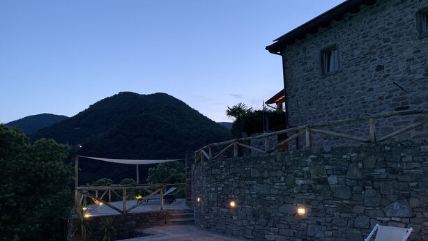 Ein Steinhaus mit Pool und Außenbereich, umgeben von Bergen.