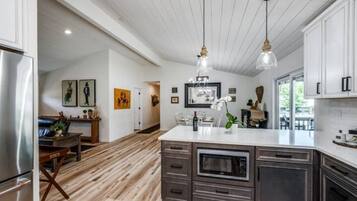 Une cuisine moderne dotée d’un îlot central, de planchers en bois et de luminaires suspendus.