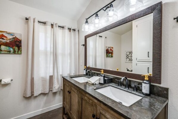 Une salle de bain avec un meuble-lavabo à deux vasques, un grand miroir et un rideau de douche.