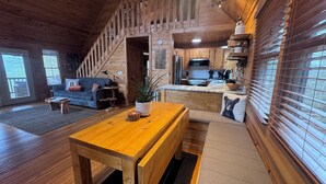 Ein gemütliches Blockhaus-Interieur mit einem Holzesstisch, einer Couch und einer Küchenzeile.