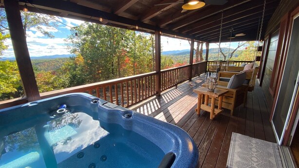 Ein Whirlpool auf einer Holzterrasse mit Blick auf einen Wald und Berge.