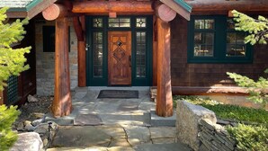 A log cabin with a stone entrance, wooden beams, and a green door. - Cayuga Lodge  (Cooperstown)