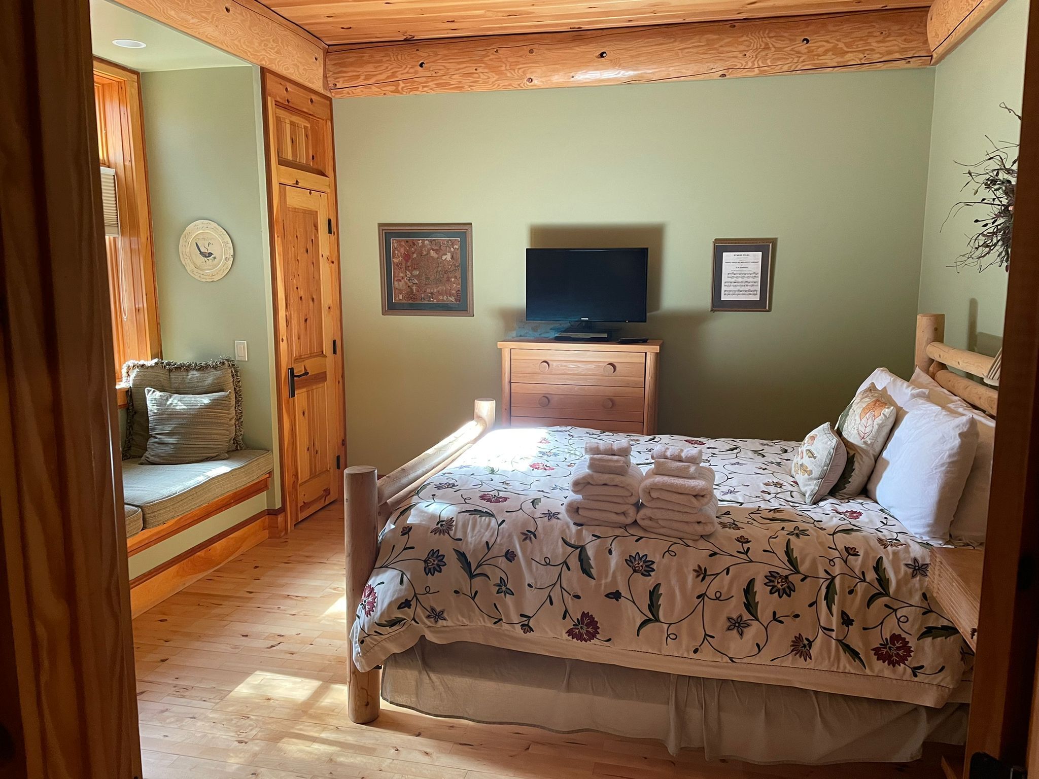 Ein Schlafzimmer mit einem Bett, einer hölzernen Kommode und einem Fernseher.