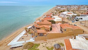 Ein Küstenwohngebiet mit Häusern mit roten Ziegeldächern, einem Strand und freiem Blick auf das Meer.