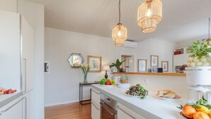 A modern kitchen with white cabinetry, a wooden countertop, and a built-in oven. There are hanging pendant lights, a fruit bowl, and a plant on the counter. - Casa Buccellato in Lucca (Lucca)