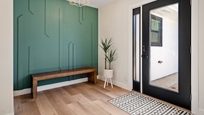 Un ingresso moderno con una panca in legno, una pianta in vaso e una porta nera con finestra.