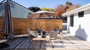 Un patio con tavolo e sedie, una recinzione in legno e una casa sullo sfondo.