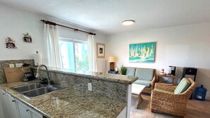 A kitchen with granite countertops, a sink, and a dining area with wicker furniture. - Infinity Poolside -  Two story Oceanview 3 Bedrooms / 3 Baths (Bimini)