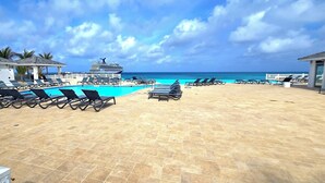 A poolside area with lounge chairs, a pool, and a view of the ocean. - Infinity Poolside -  Two story Oceanview 3 Bedrooms / 3 Baths (Bimini)