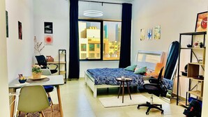 A modern bedroom with a bed, desk, and chair, a large window with a city view, and a bookshelf. - Relaxing, minimal luxurious and safe space vibe in the central area of Dubai.
 (Dubai)