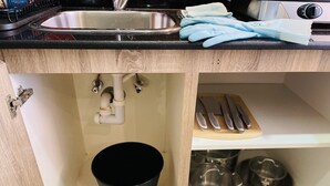 A kitchen with a stainless steel sink, a black cup, and a wooden cutting board with knives. - Relaxing, minimal luxurious and safe space vibe in the central area of Dubai.
 (Dubai)