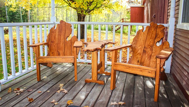 A wooden deck with Adirondack chairs and a table, surrounded by a white railing. - Northstar Lodge - 4000 sq ft + Year-Round Hot Tub (Marquette)