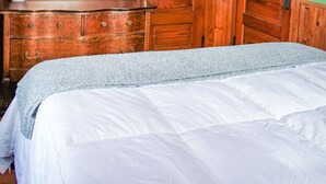 A bedroom with a wooden dresser, a large mirror, and a bed with white bedding. - Northstar Lodge - 4000 sq ft + Year-Round Hot Tub (Marquette)