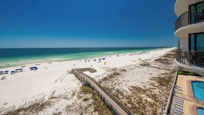 A beach view from a hotel balcony with a pool and a wooden boardwalk leading to the beach. - Beautiful Gulf Front Condo - Phoenix IX 506 (Orange Beach)