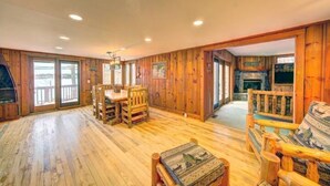 A spacious room with wooden walls and floors, a dining area with a table and chairs, and a fireplace. - Pet Friendly Lakefront Cabin
 (Tafton)