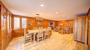 A wooden interior with a dining table and chairs, a sofa, and a television. - Pet Friendly Lakefront Cabin
 (Tafton)